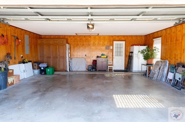 garage featuring wooden walls, white refrigerator with ice dispenser, electric panel, and a garage door opener