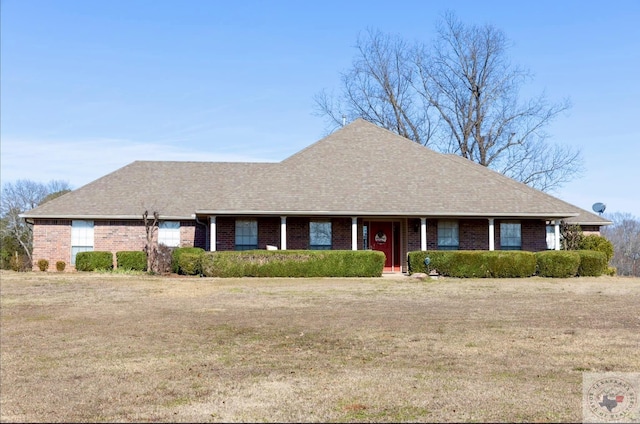 ranch-style home with brick siding, a front lawn, and a shingled roof