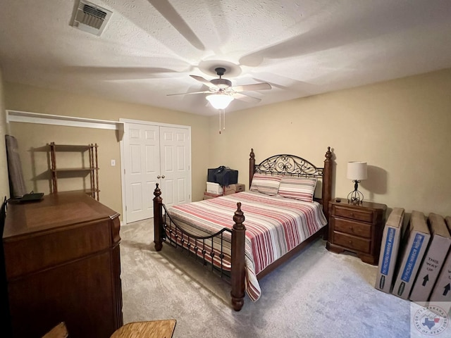 carpeted bedroom featuring ceiling fan, a textured ceiling, a closet, and visible vents