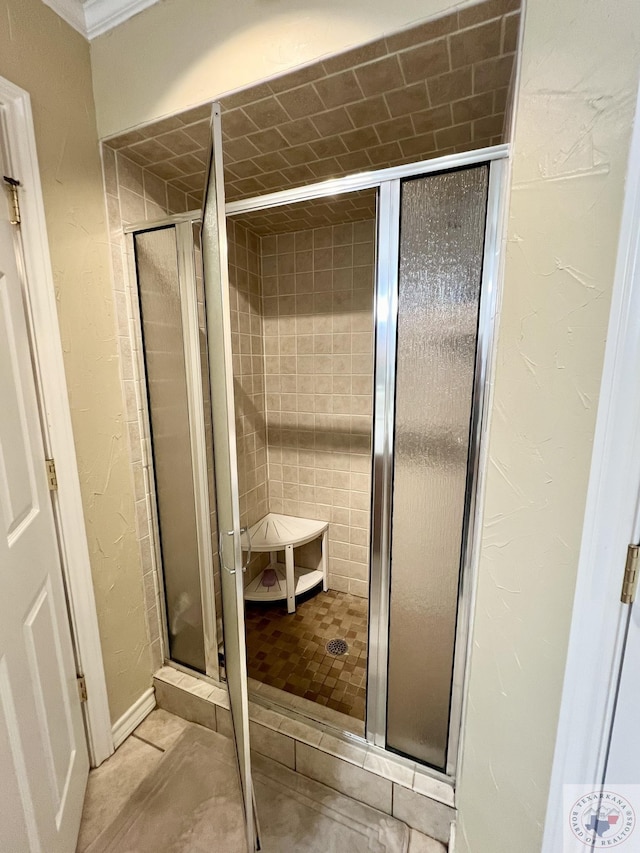 bathroom with a textured wall and a stall shower