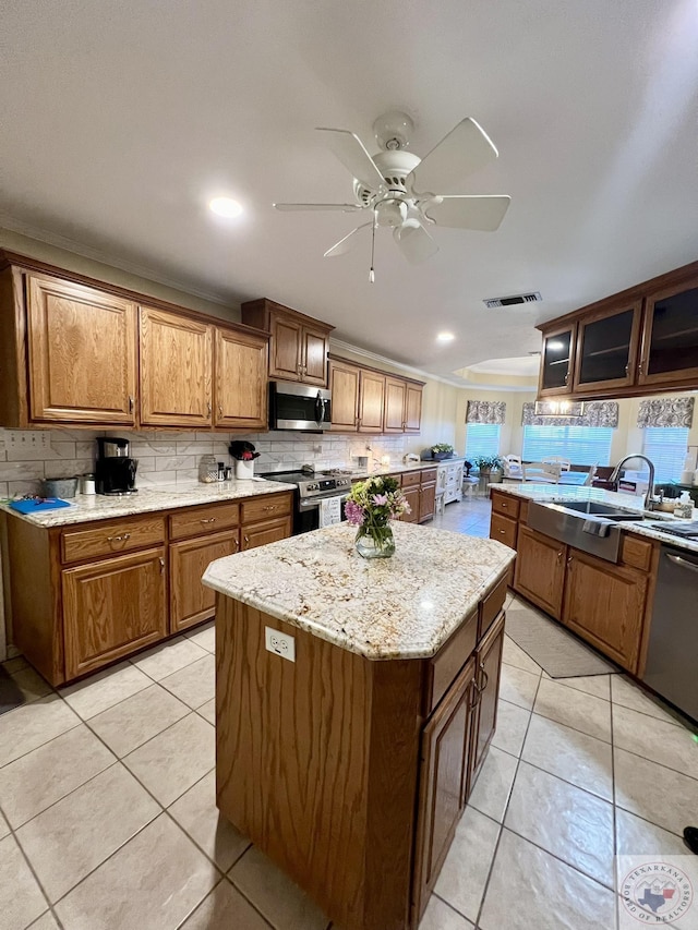 kitchen featuring brown cabinets, a kitchen island, glass insert cabinets, and stainless steel appliances