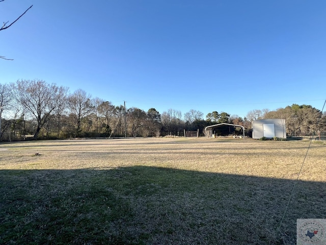 view of yard with a detached carport, an outdoor structure, and a storage shed