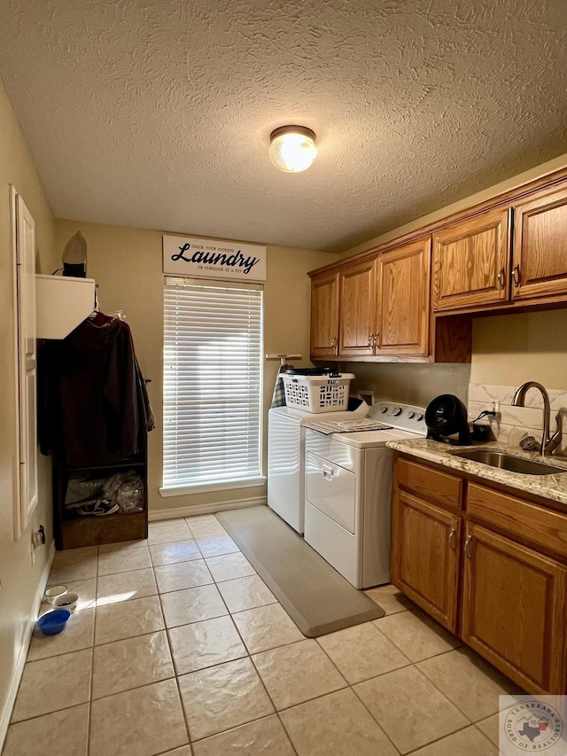 laundry area featuring washing machine and dryer, cabinet space, a sink, and light tile patterned floors