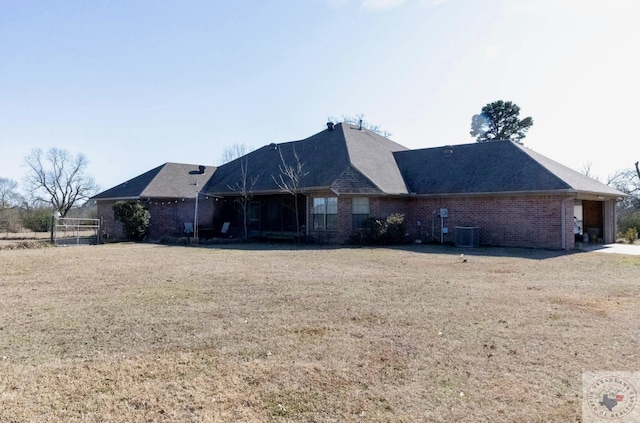 rear view of house featuring a yard, brick siding, and central AC