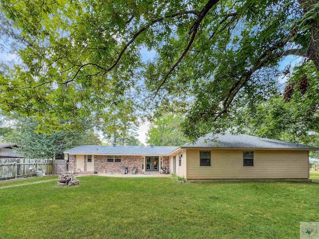 rear view of property featuring a patio area, a fire pit, and a lawn