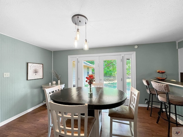 dining area featuring a textured ceiling, dark hardwood / wood-style floors, and french doors