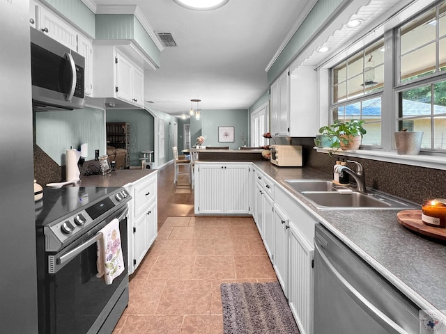 kitchen featuring white cabinetry, hanging light fixtures, light tile patterned floors, sink, and stainless steel appliances