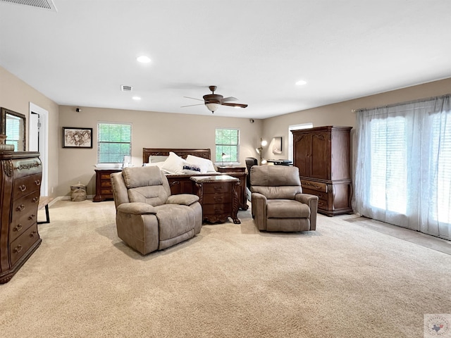 bedroom with ceiling fan, light carpet, and multiple windows