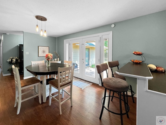 dining space with french doors, dark hardwood / wood-style flooring, and a textured ceiling