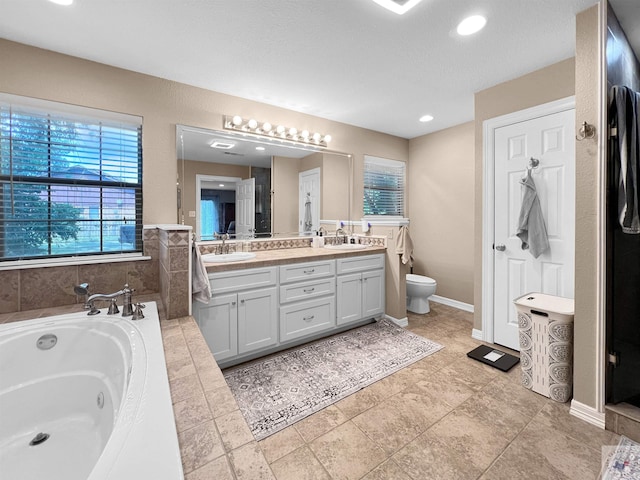 bathroom featuring vanity, toilet, and tiled bath