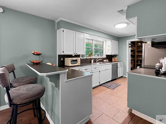 kitchen featuring a kitchen bar, dishwasher, white cabinetry, ornamental molding, and kitchen peninsula