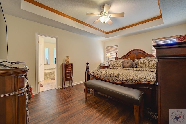 bedroom with crown molding, a raised ceiling, ceiling fan, connected bathroom, and dark hardwood / wood-style floors