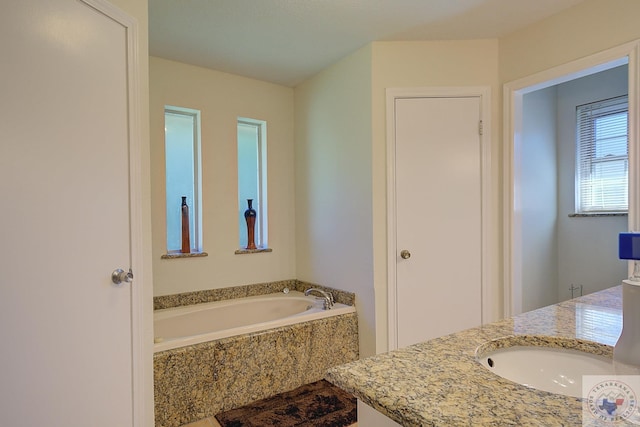 bathroom with tiled tub and vanity