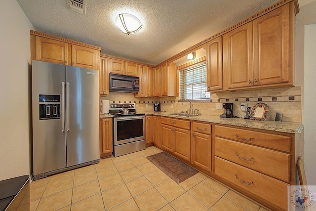 kitchen with light stone countertops, a textured ceiling, stainless steel appliances, sink, and light tile patterned floors