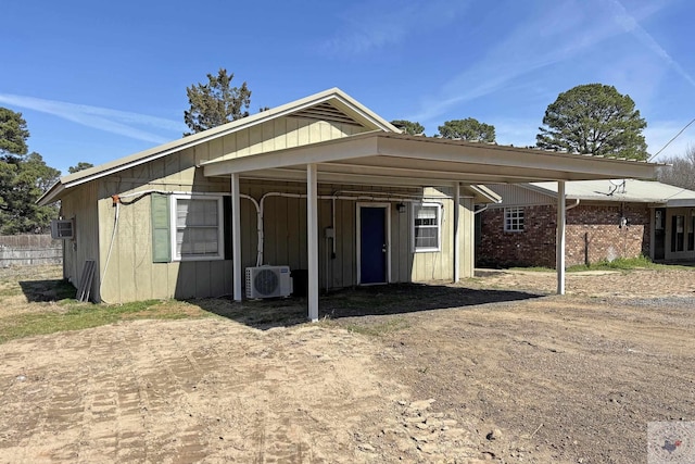 view of front of home featuring dirt driveway, a carport, ac unit, and board and batten siding