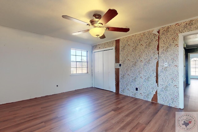 unfurnished bedroom with a closet, ceiling fan, multiple windows, and wood-type flooring