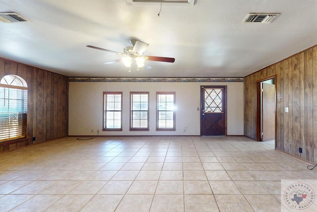 entryway with a wealth of natural light, wooden walls, and light tile patterned floors