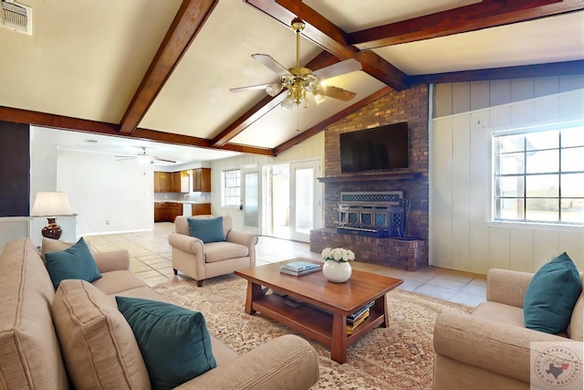 living room with a fireplace, light tile patterned floors, ceiling fan, and vaulted ceiling with beams