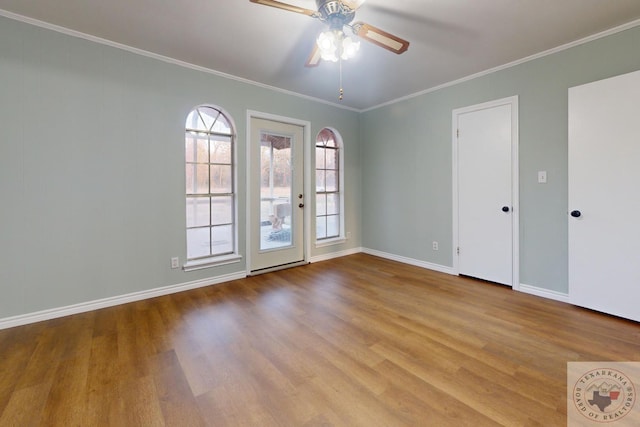 unfurnished room with ornamental molding, wood finished floors, a ceiling fan, and baseboards