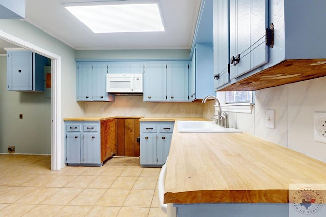 kitchen featuring light countertops, white microwave, light tile patterned flooring, a sink, and electric panel