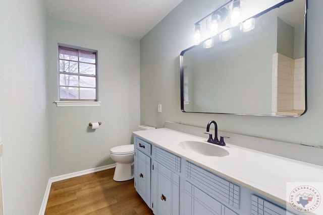 bathroom with toilet, vanity, baseboards, and wood finished floors