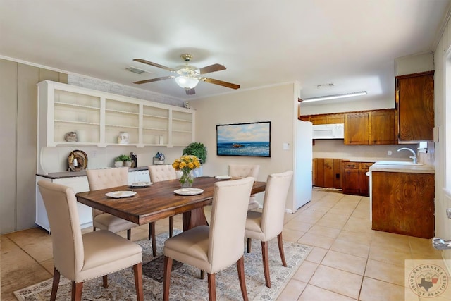 tiled dining space featuring ceiling fan, sink, and crown molding