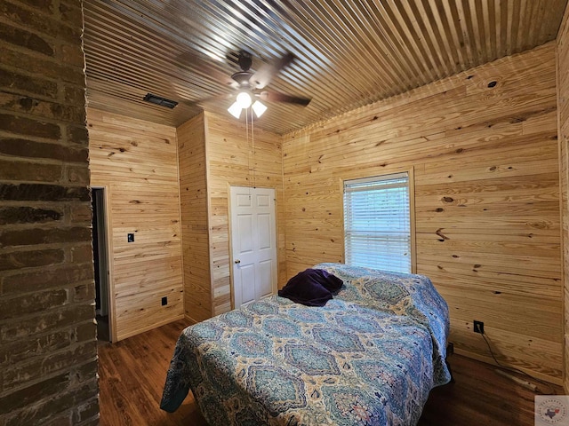 bedroom with ceiling fan, wood walls, dark wood-type flooring, and wooden ceiling