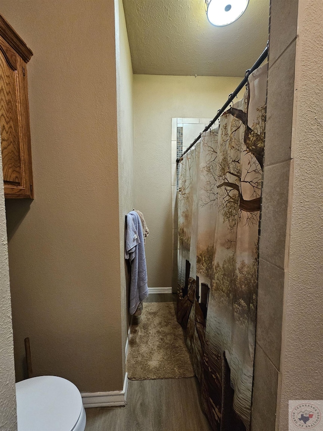 bathroom featuring hardwood / wood-style flooring, a textured ceiling, toilet, and a shower with shower curtain