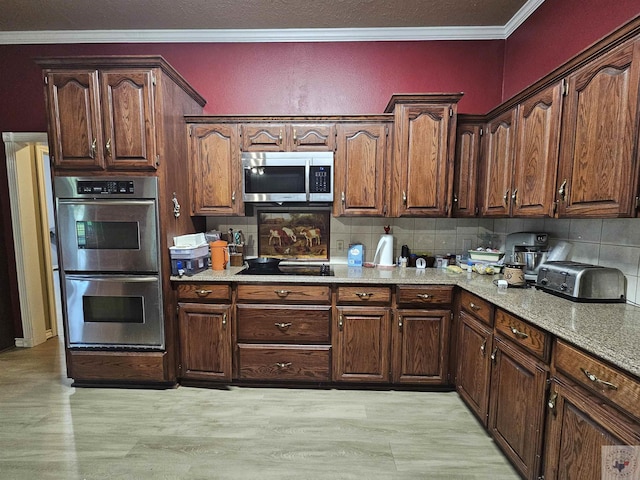 kitchen with crown molding, light wood-type flooring, light stone counters, decorative backsplash, and stainless steel appliances