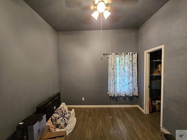 interior space with a textured ceiling, ceiling fan, and dark hardwood / wood-style flooring