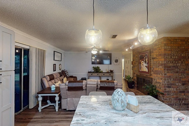 dining room featuring ceiling fan, dark wood-type flooring, a textured ceiling, and ornamental molding