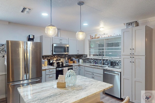 kitchen with light stone counters, sink, appliances with stainless steel finishes, and a center island