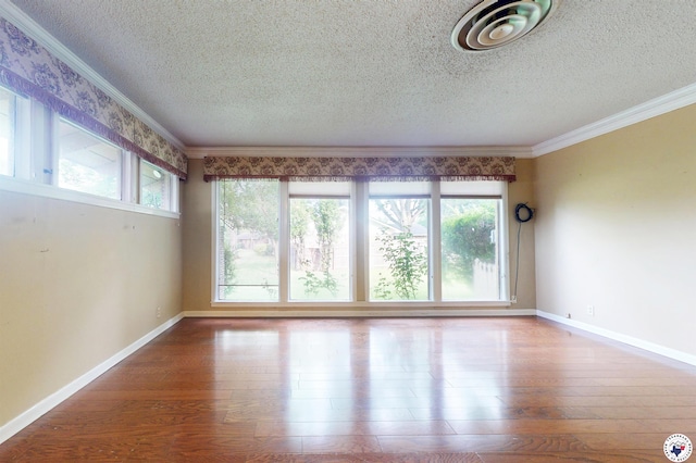 1315 Holloway Dr, Texarkana, TX 75503 - empty room featuring a textured ceiling, plenty of natural light, ornamental molding, and wood finished floors