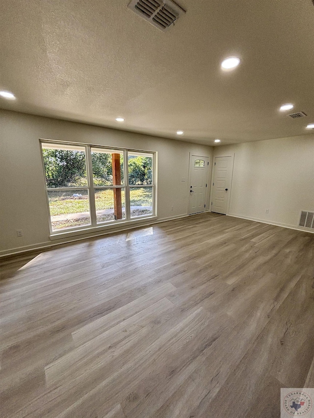 empty room with light hardwood / wood-style flooring and a textured ceiling