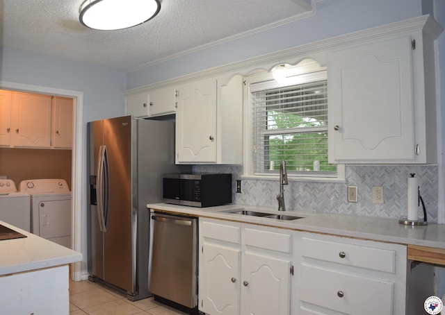 kitchen featuring stainless steel appliances, light countertops, a sink, separate washer and dryer, and a textured ceiling