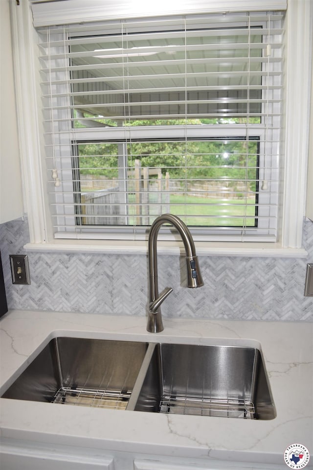 interior details with light stone countertops, a sink, and backsplash