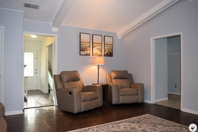 living area featuring baseboards, wood finished floors, visible vents, and vaulted ceiling with beams