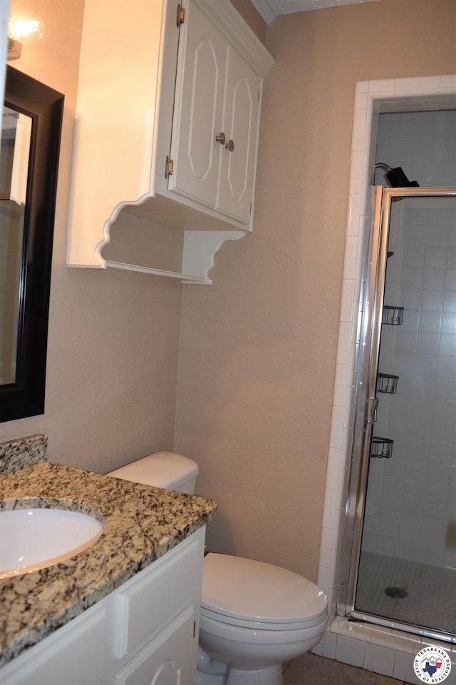 bathroom with a shower stall, toilet, and vanity