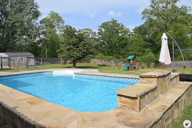 view of pool with a fenced in pool, an outbuilding, a fenced backyard, a playground, and a lawn