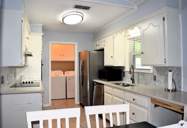 kitchen featuring backsplash, visible vents, a sink, washing machine and dryer, and black appliances