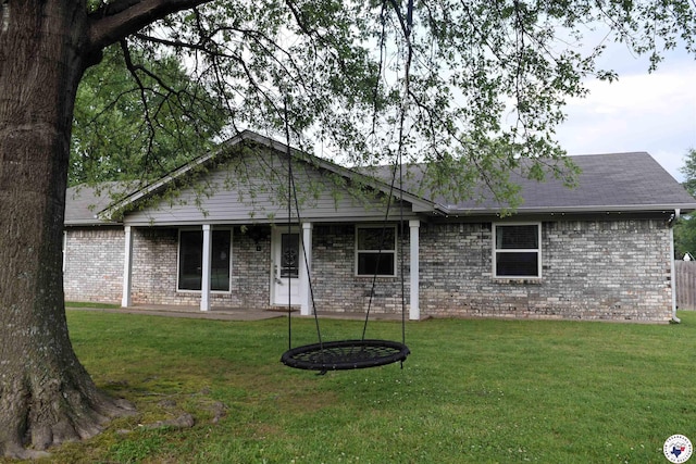 view of front facade featuring brick siding, a front yard, and a patio