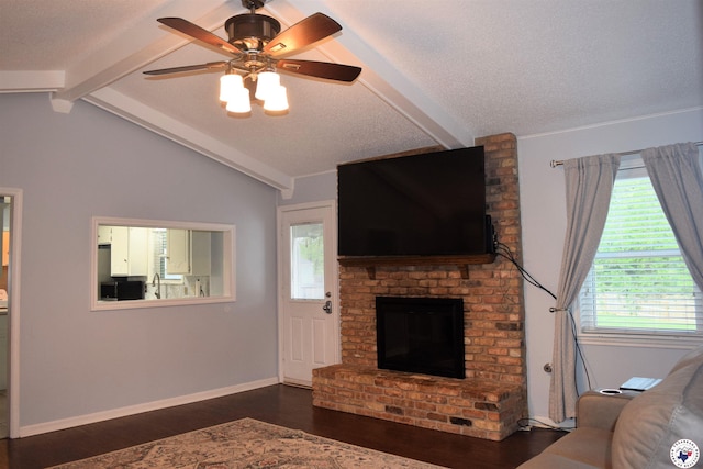 living room with a textured ceiling, dark wood-style flooring, vaulted ceiling with beams, a ceiling fan, and a fireplace