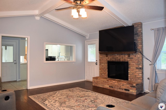 living area featuring lofted ceiling with beams, baseboards, wood finished floors, ceiling fan, and a fireplace