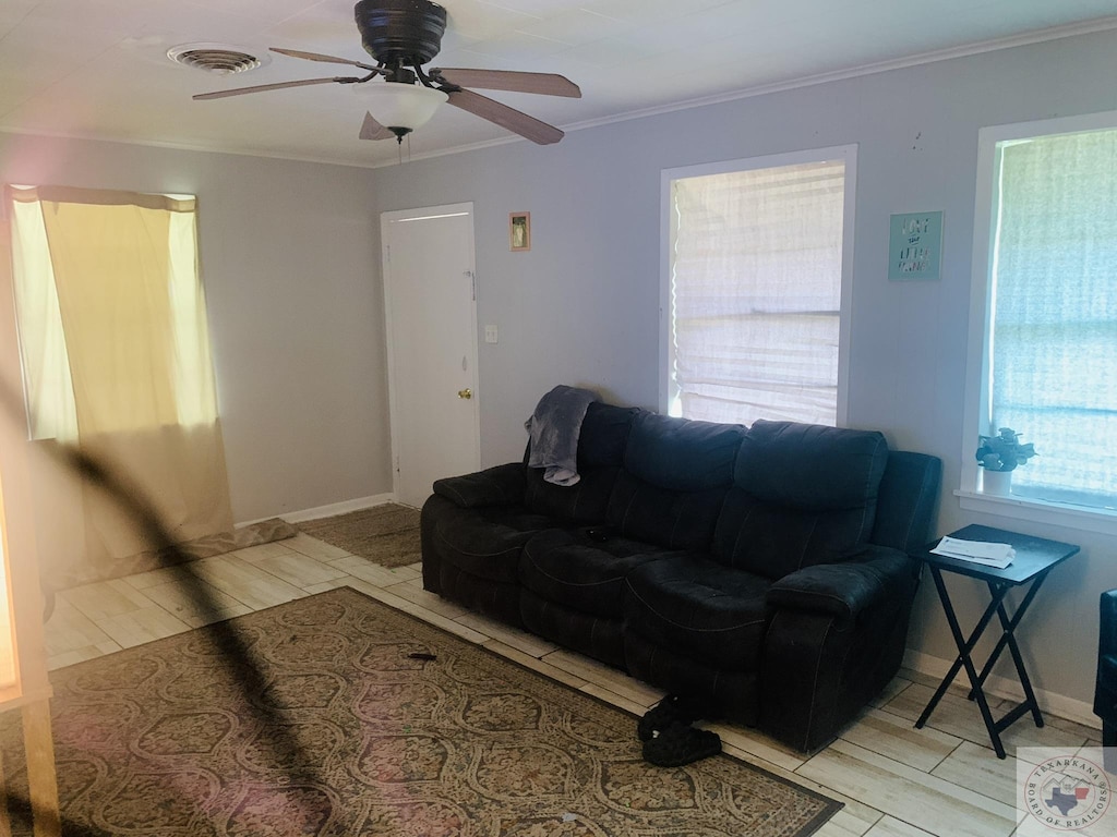 living room featuring ceiling fan, ornamental molding, and plenty of natural light