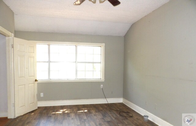 spare room with dark wood-type flooring, a textured ceiling, and lofted ceiling