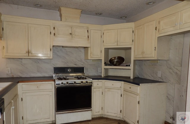 kitchen featuring dishwasher, wood-type flooring, decorative backsplash, cream cabinets, and gas range oven