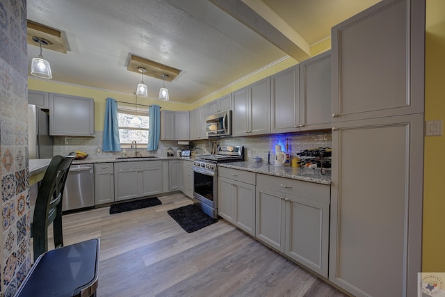 kitchen with sink, appliances with stainless steel finishes, gray cabinets, and hanging light fixtures