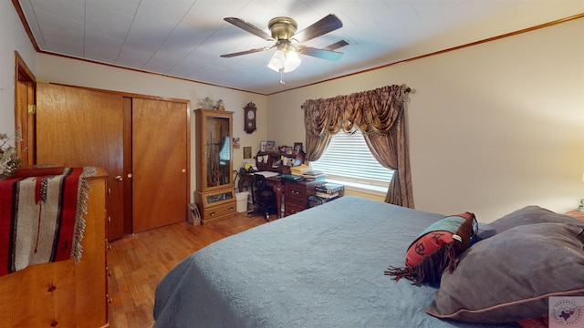 bedroom featuring crown molding, light hardwood / wood-style floors, and ceiling fan