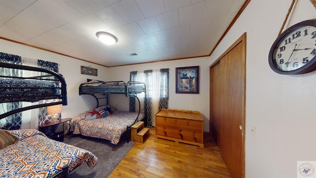 bedroom with a closet, light hardwood / wood-style flooring, and crown molding