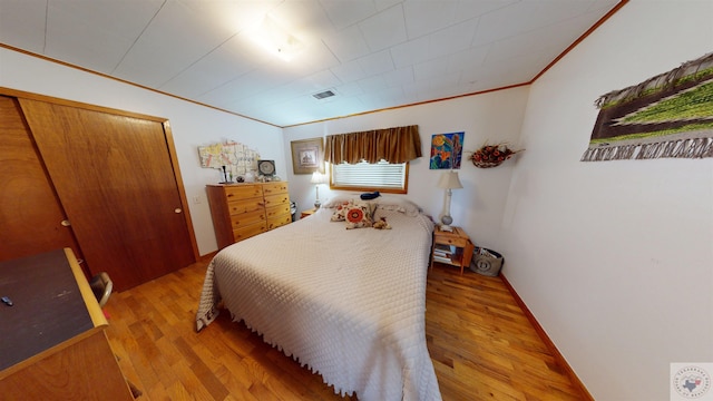 bedroom with crown molding, light wood-type flooring, and a closet